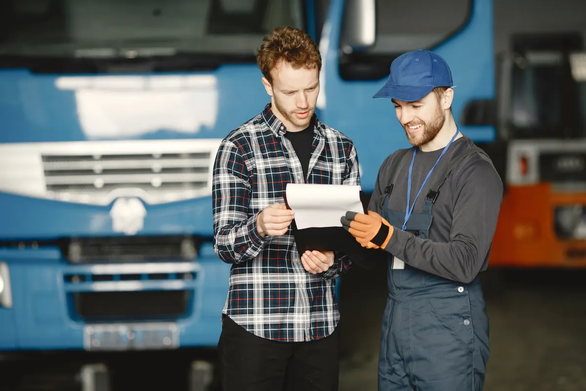 Two people reviewing paperwork beside a truck